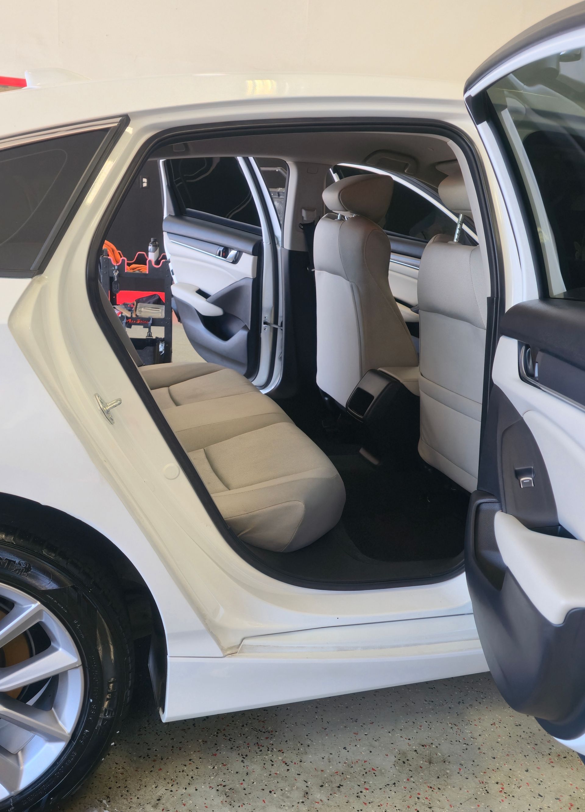 White car interior with open doors, light-colored seats, and a cleaning kit visible.