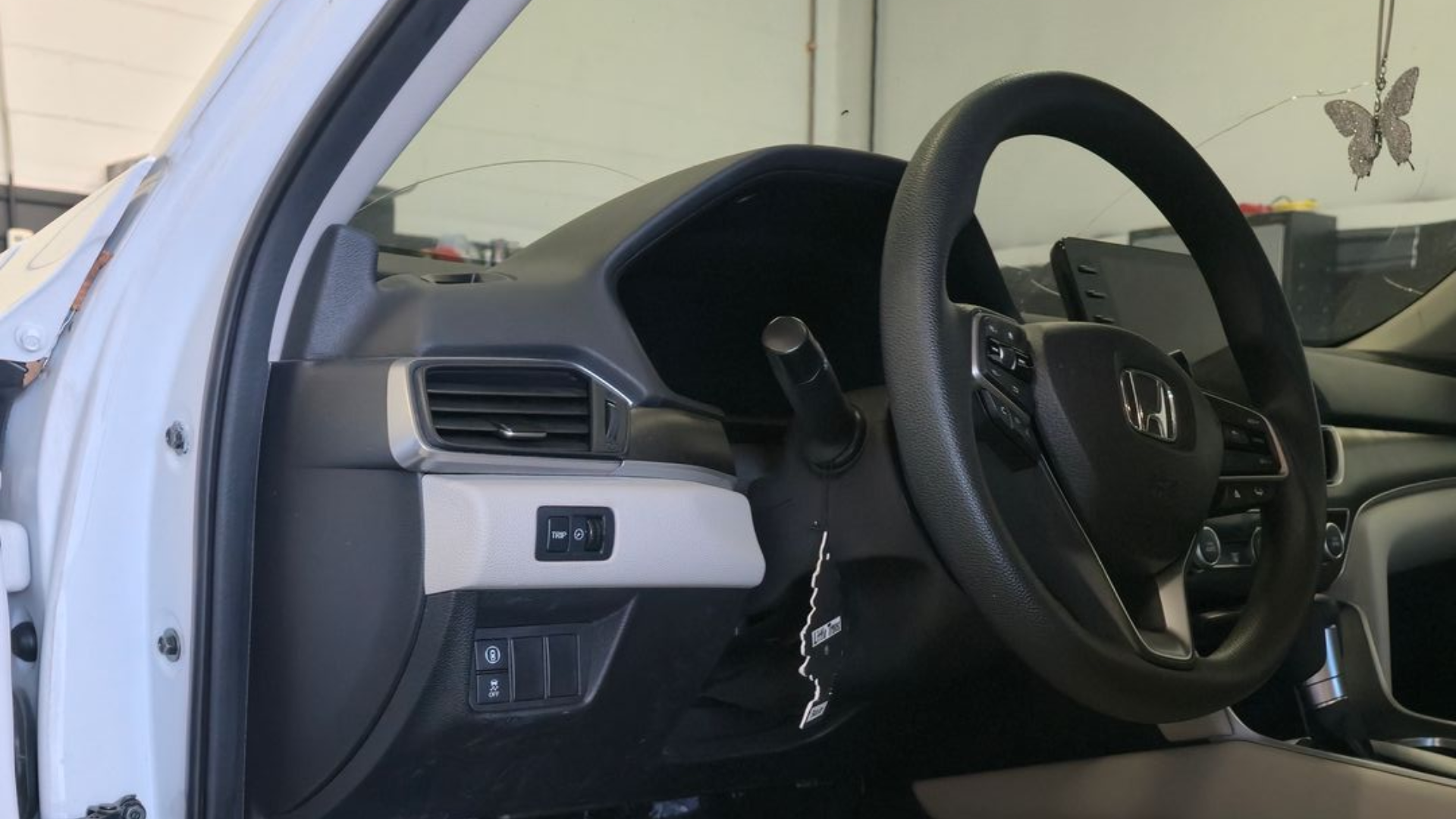 Interior car view: steering wheel, driver's seat, dashboard, and open door.