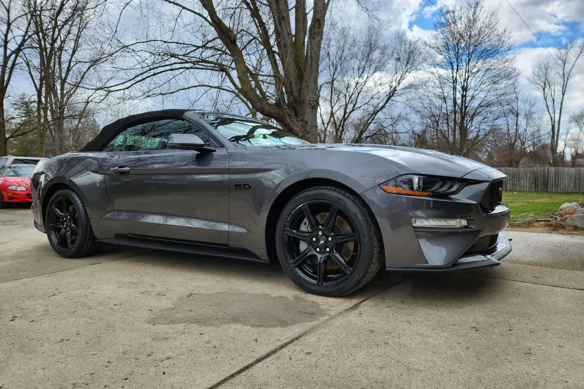 Dark gray Ford Mustang sports car on a paved road.