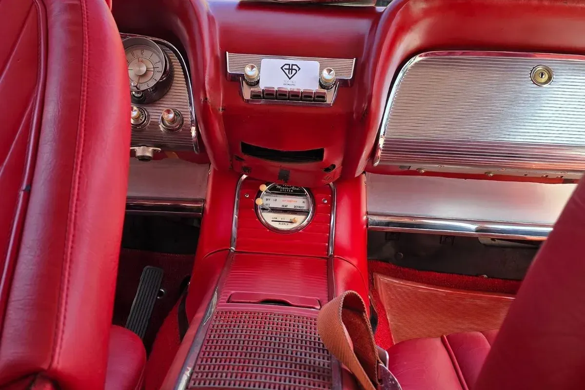 Red interior of a classic car; seats, dashboard, and center console are visible.