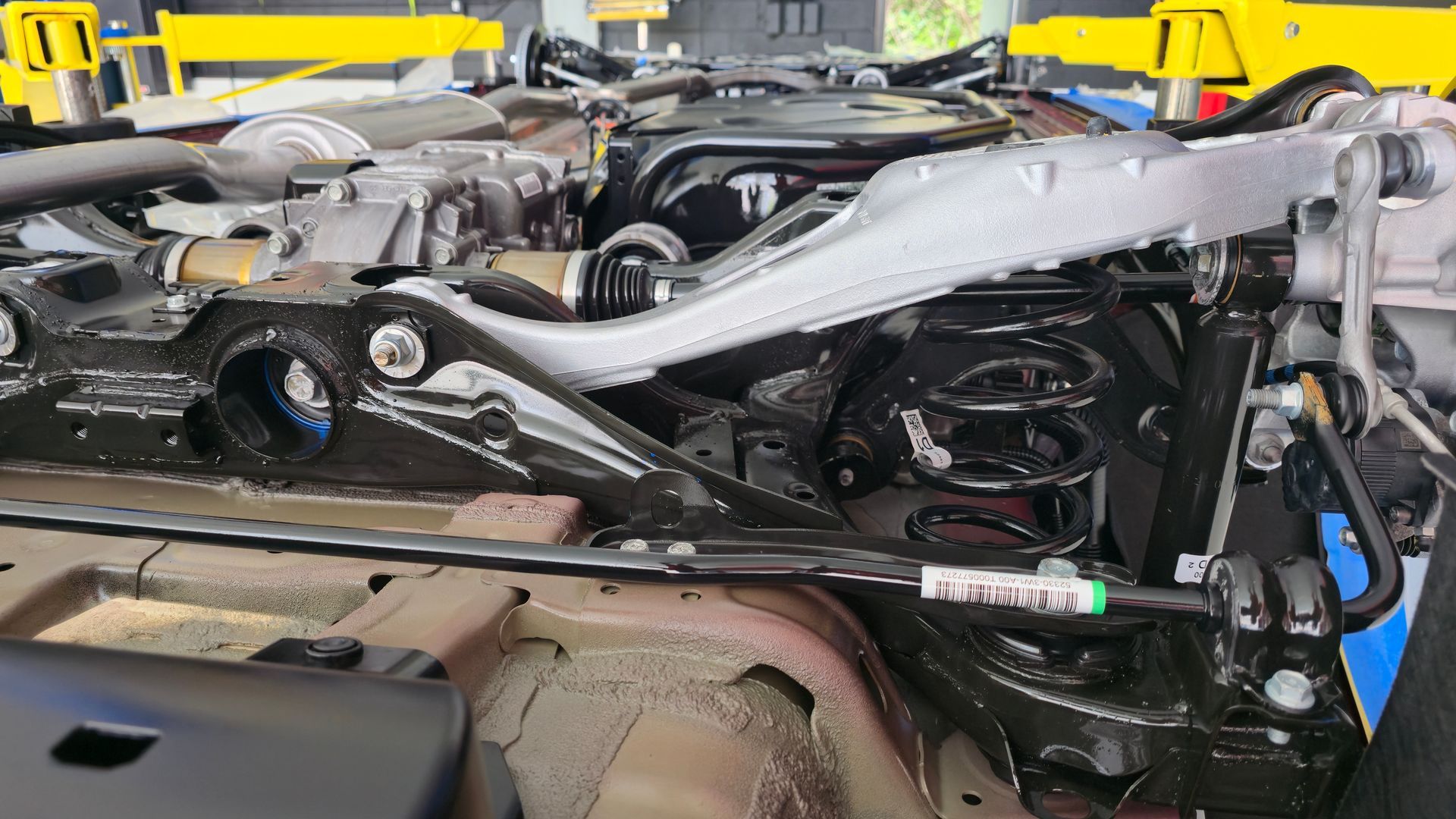Car chassis being worked on in a shop, showing suspension components, black and silver.
