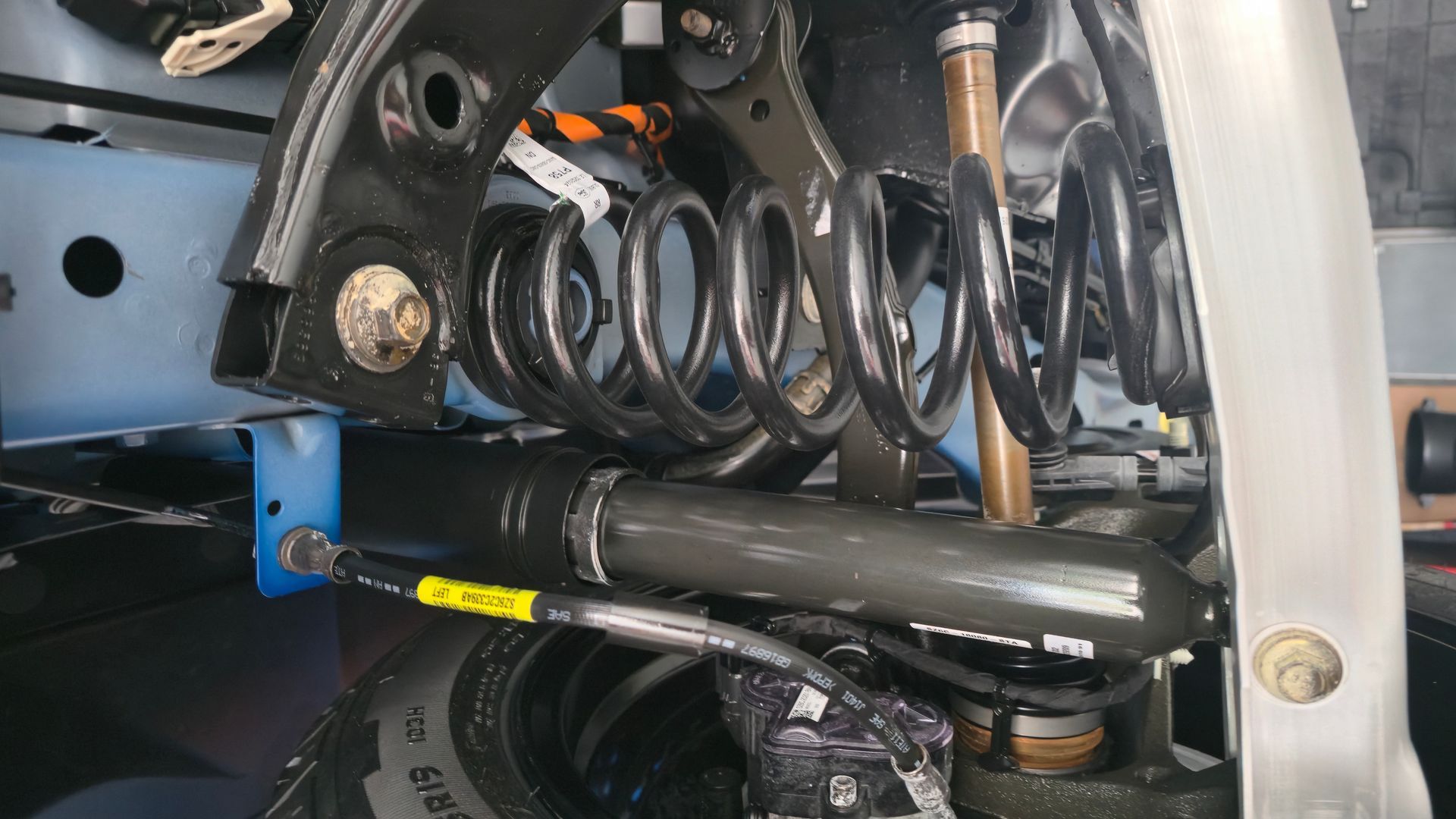 Black suspension coil and shock absorber in a vehicle, blue support beam.