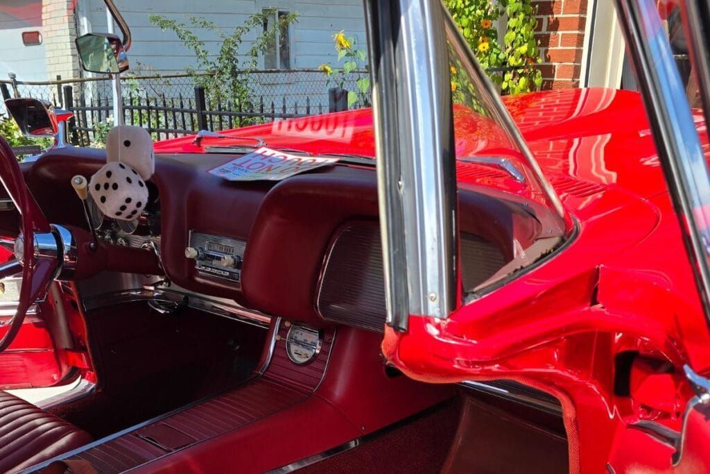 Red vintage car interior with fuzzy dice hanging.