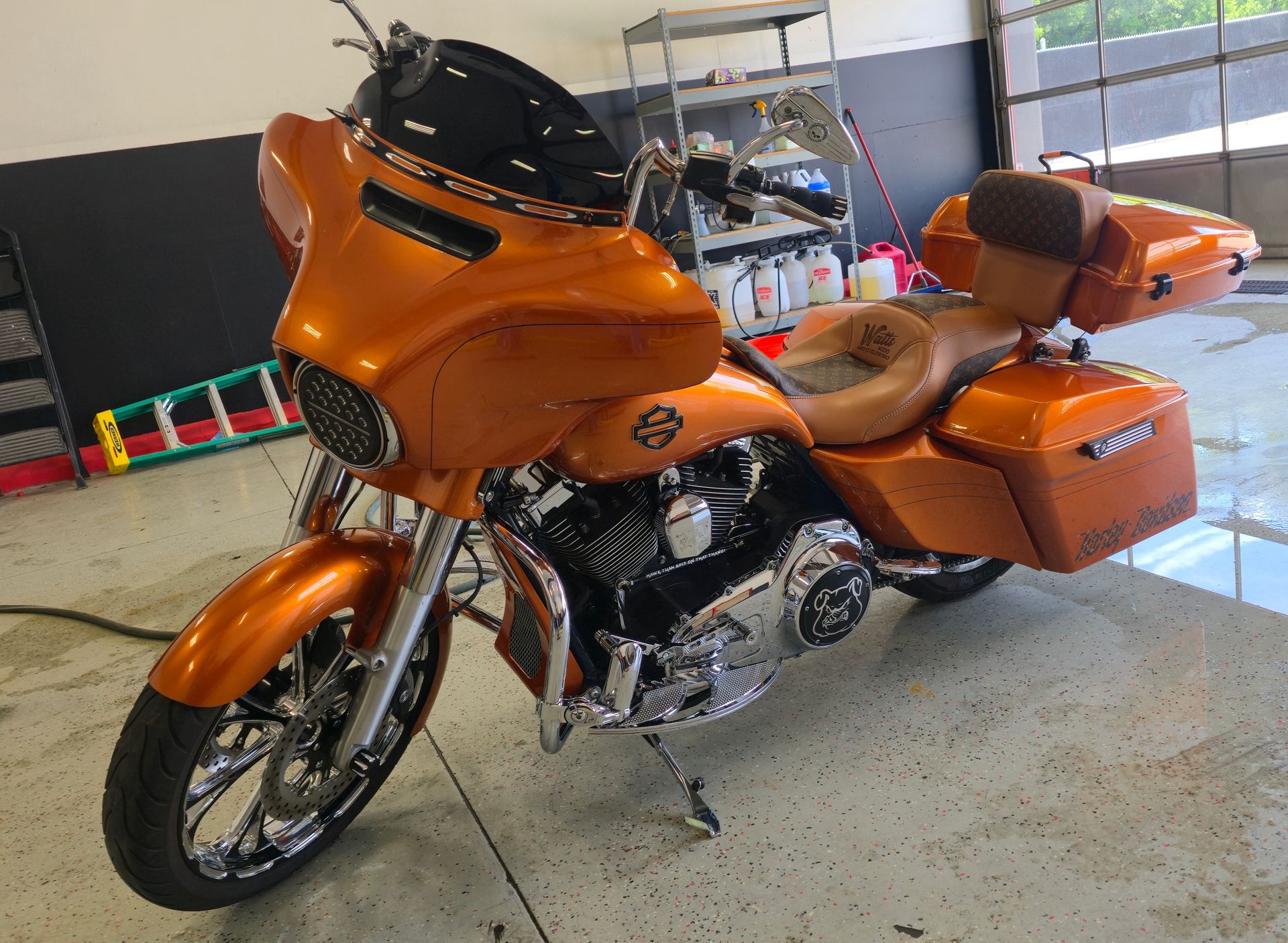 Orange custom motorcycle with chrome details, in a shop setting.