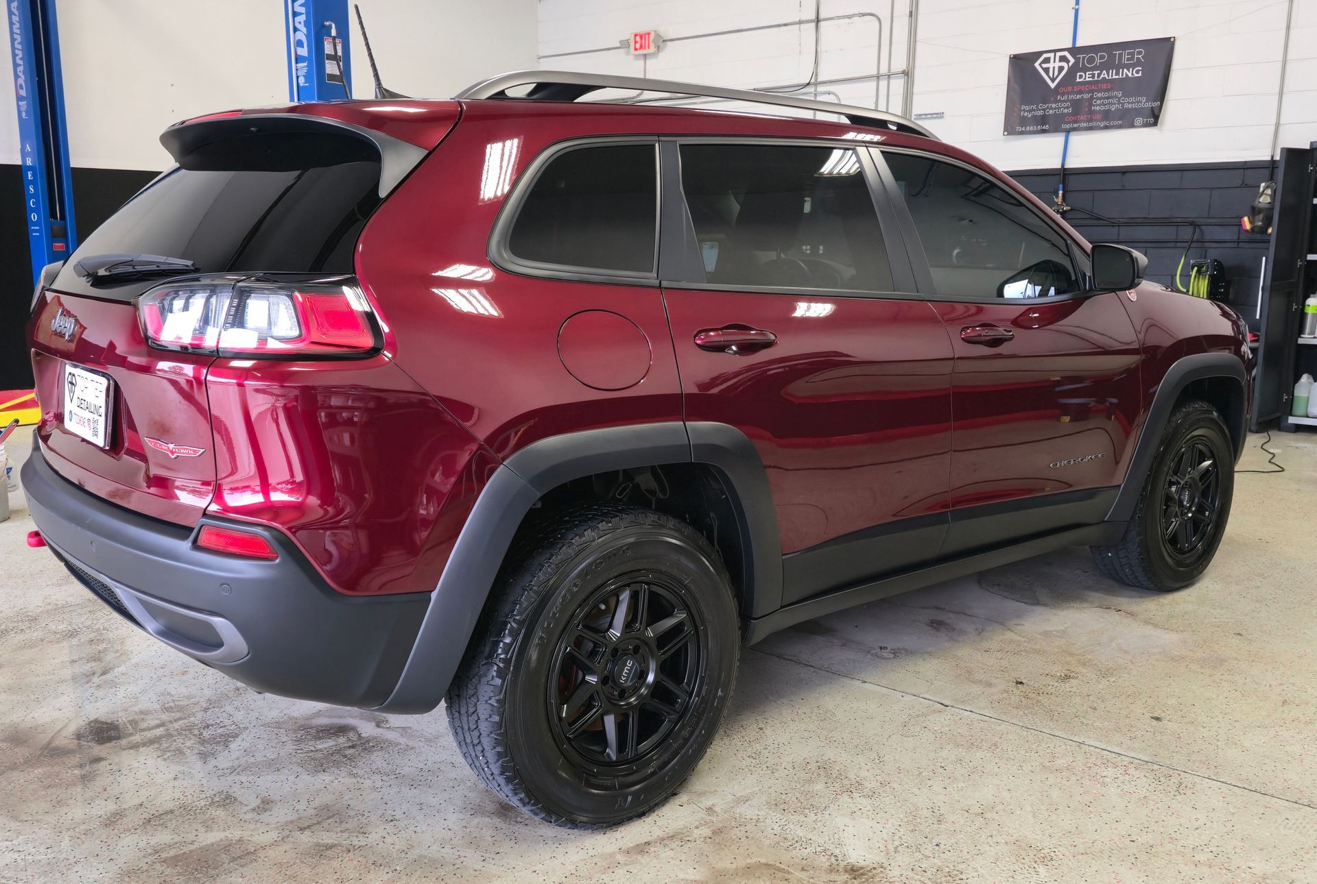 Maroon Jeep Cherokee SUV in an auto shop, parked on a concrete floor.
