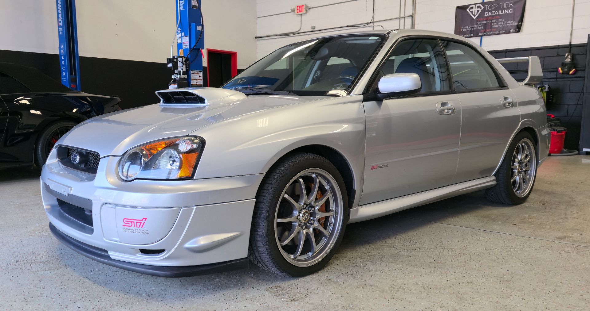 Silver Subaru Impreza WRX parked in a garage with custom front bumper.