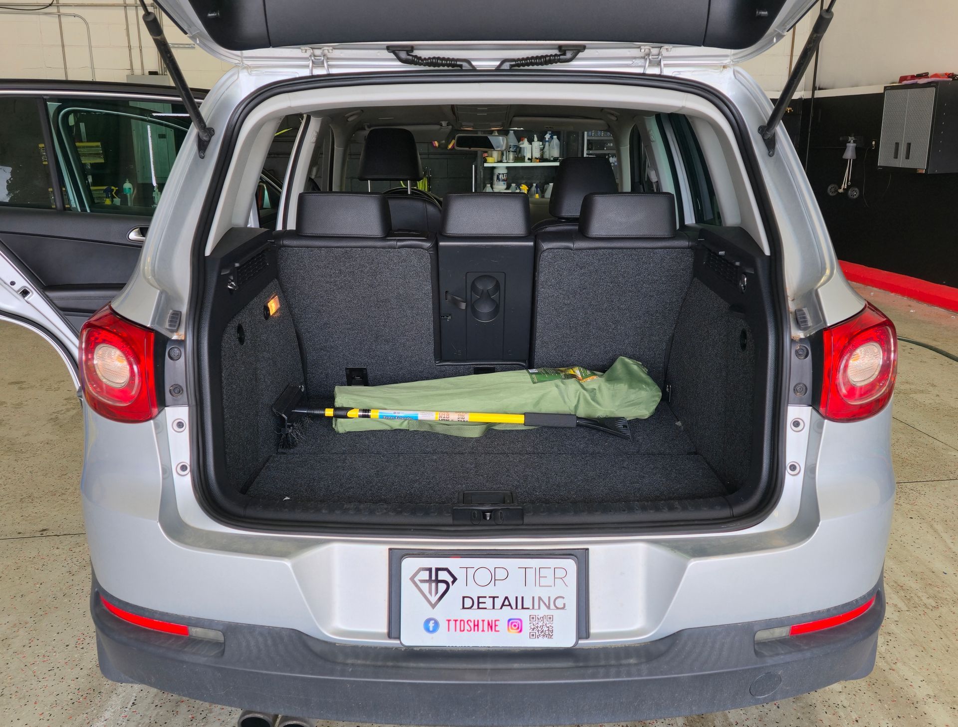 Open rear of silver SUV with seats folded down, revealing spare tire and cargo area.