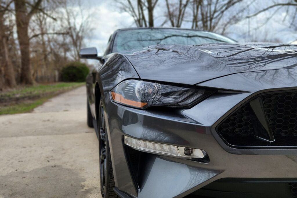 Gray Ford Mustang parked on a paved path, front view, daytime.