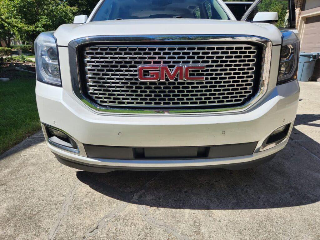 White GMC Yukon SUV, front view, parked on concrete driveway, with the GMC logo visible.