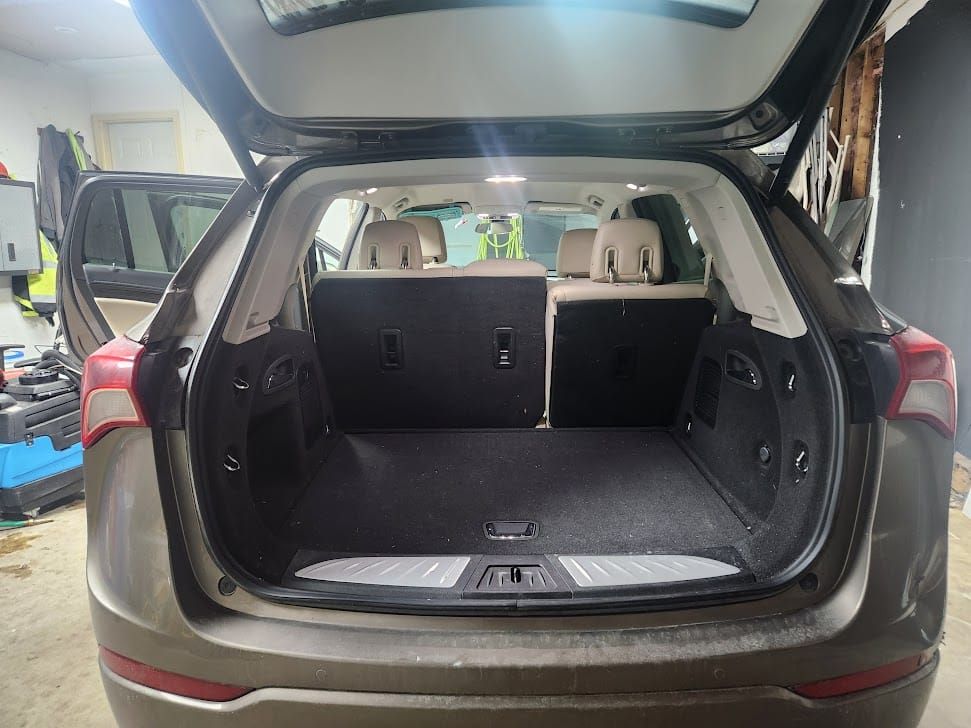 Brown SUV cargo area with seats folded down and open door.