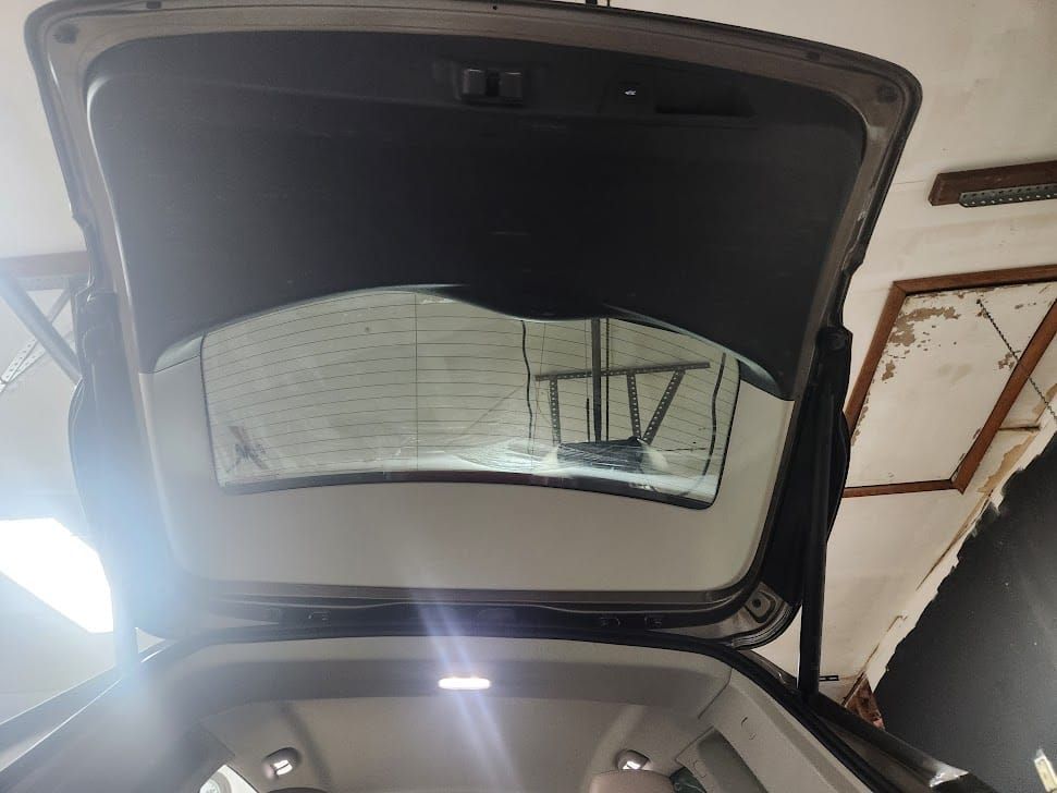 Open trunk of a car, revealing rear window. Interior lights glow.