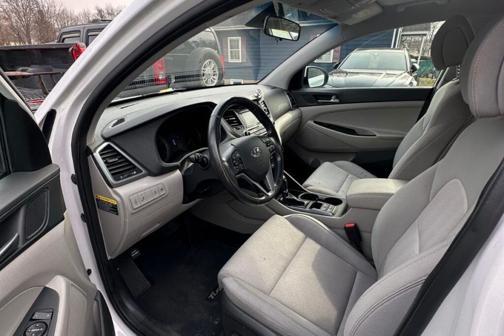 Interior view of a white Hyundai Tucson, showing seats, steering wheel, and dashboard.