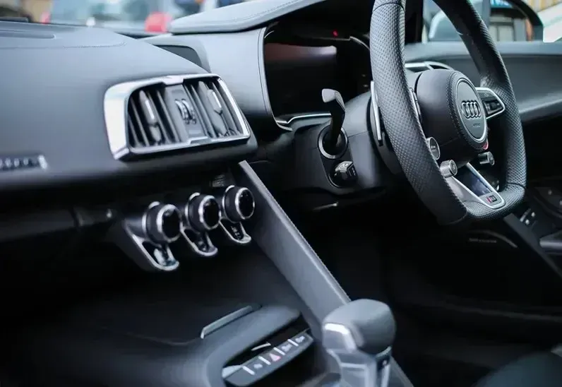 Interior of a black Audi car, showing dashboard, steering wheel, air vents, and controls.