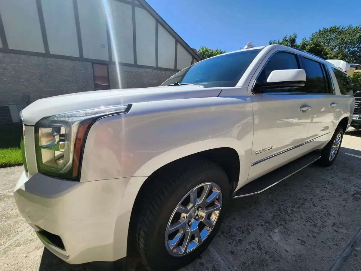 White GMC Yukon SUV parked on concrete driveway, sunny outdoor setting.