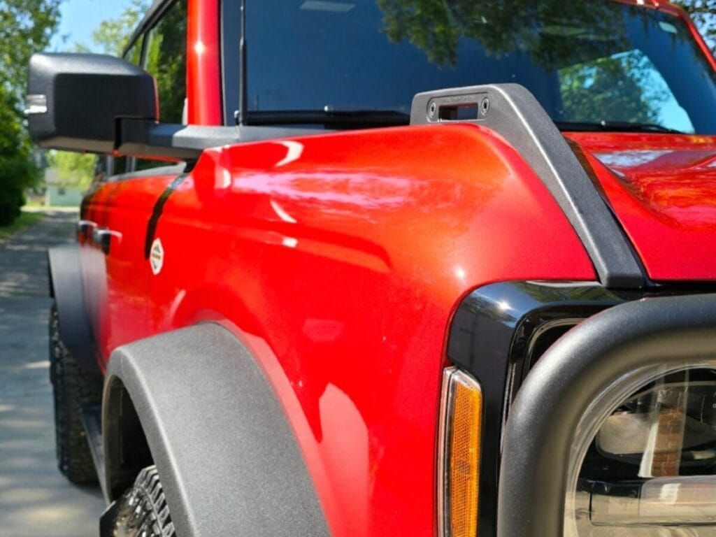 Red Ford Bronco with a snorkel on the front fender, parked outside on a sunny day.