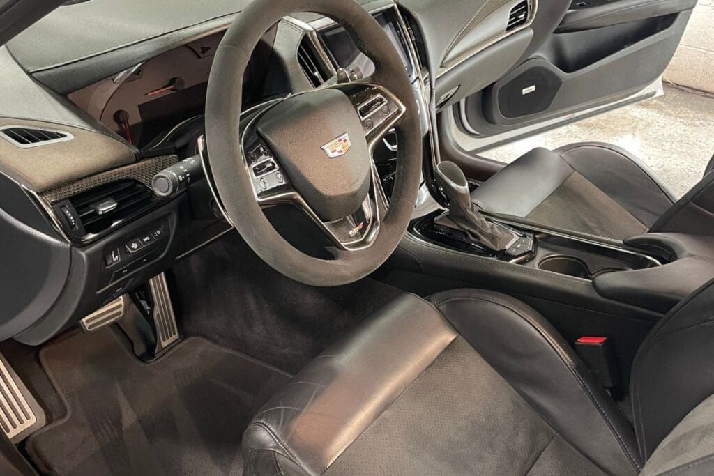 Cadillac car interior with a steering wheel, dashboard, seats, and center console.
