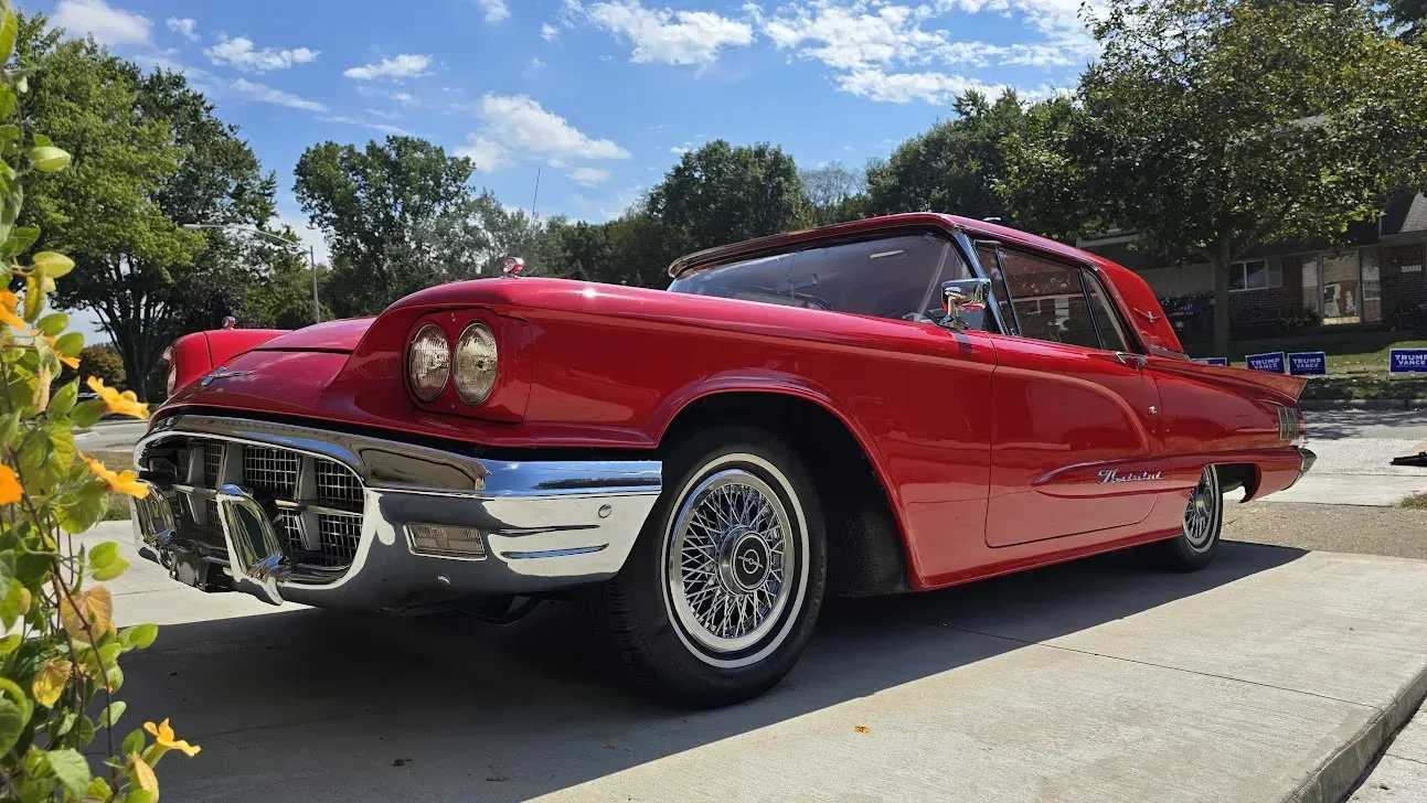 Red 1958 Ford Thunderbird coupe parked on a concrete surface, with chrome accents.