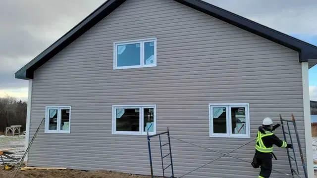 Un homme est debout sur une échelle devant une maison.