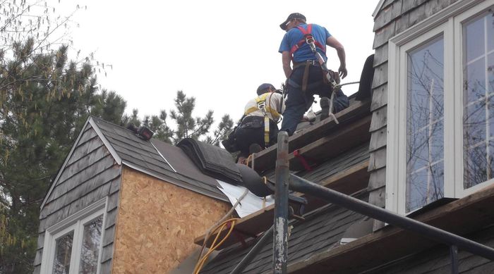 Deux hommes travaillent sur le toit d une maison.