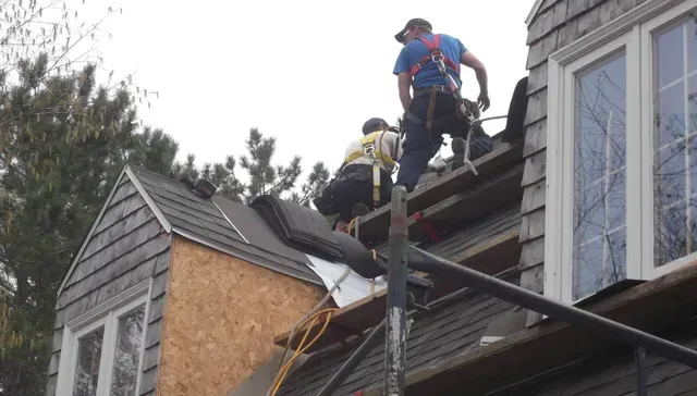 Deux hommes travaillent sur le toit d'une maison.