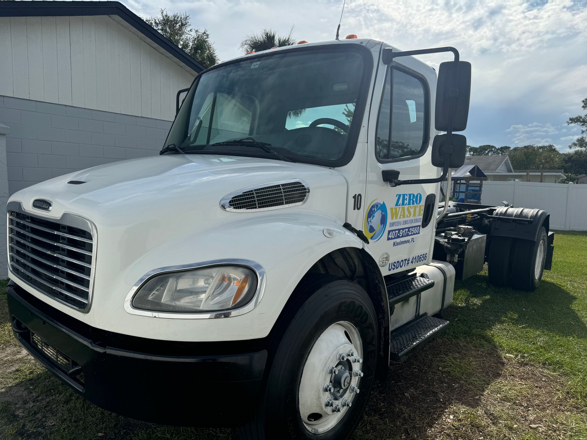White semi-truck parked on grass with company logo on the side.