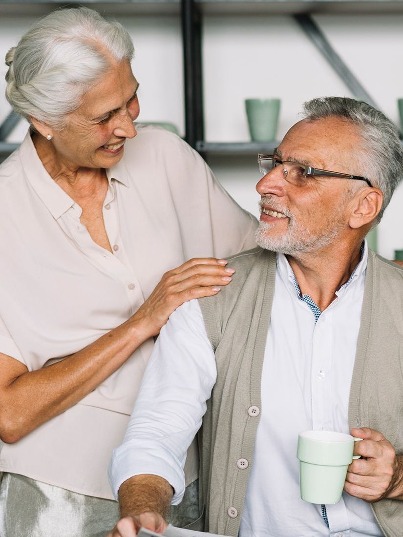 A man and a woman are sitting next to each other holding cups of coffee.