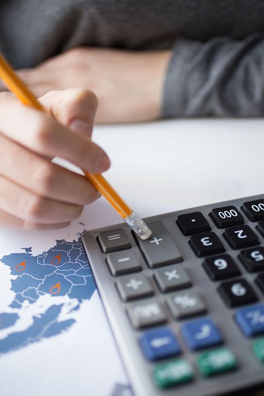 A person is using a calculator and writing on a map.