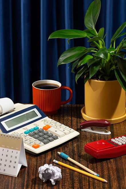 A desk with a calculator , pencils , a cup of coffee , and a plant.