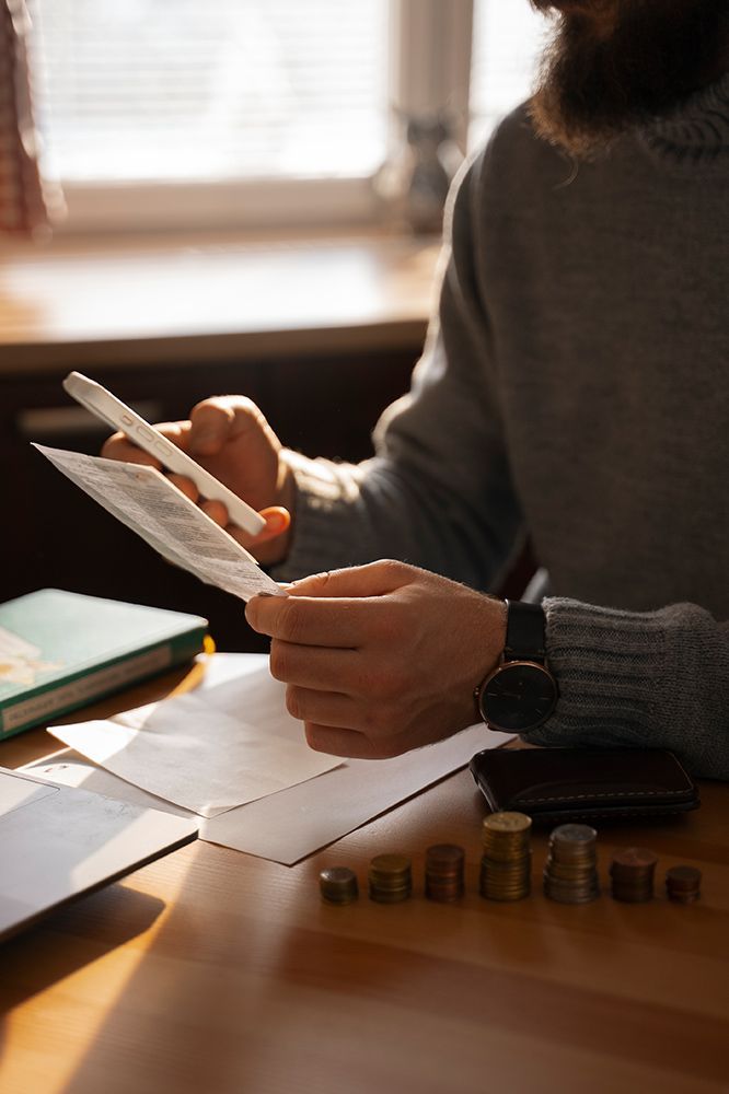 A man is sitting at a table holding a pen and a piece of paper.