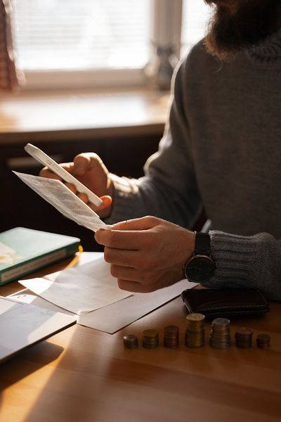 A man is sitting at a table holding a pen and a piece of paper.