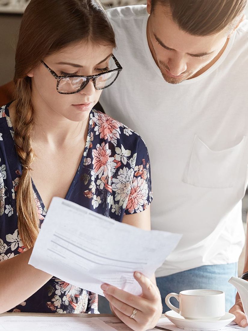 A man and a woman are sitting at a table looking at a piece of paper.