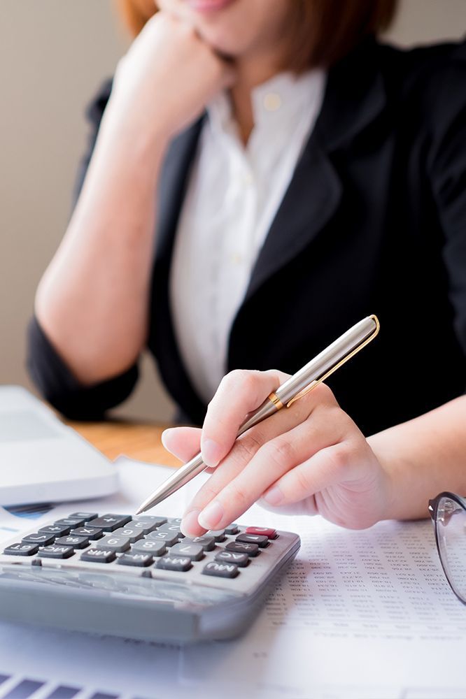 A woman is using a calculator while holding a pen.