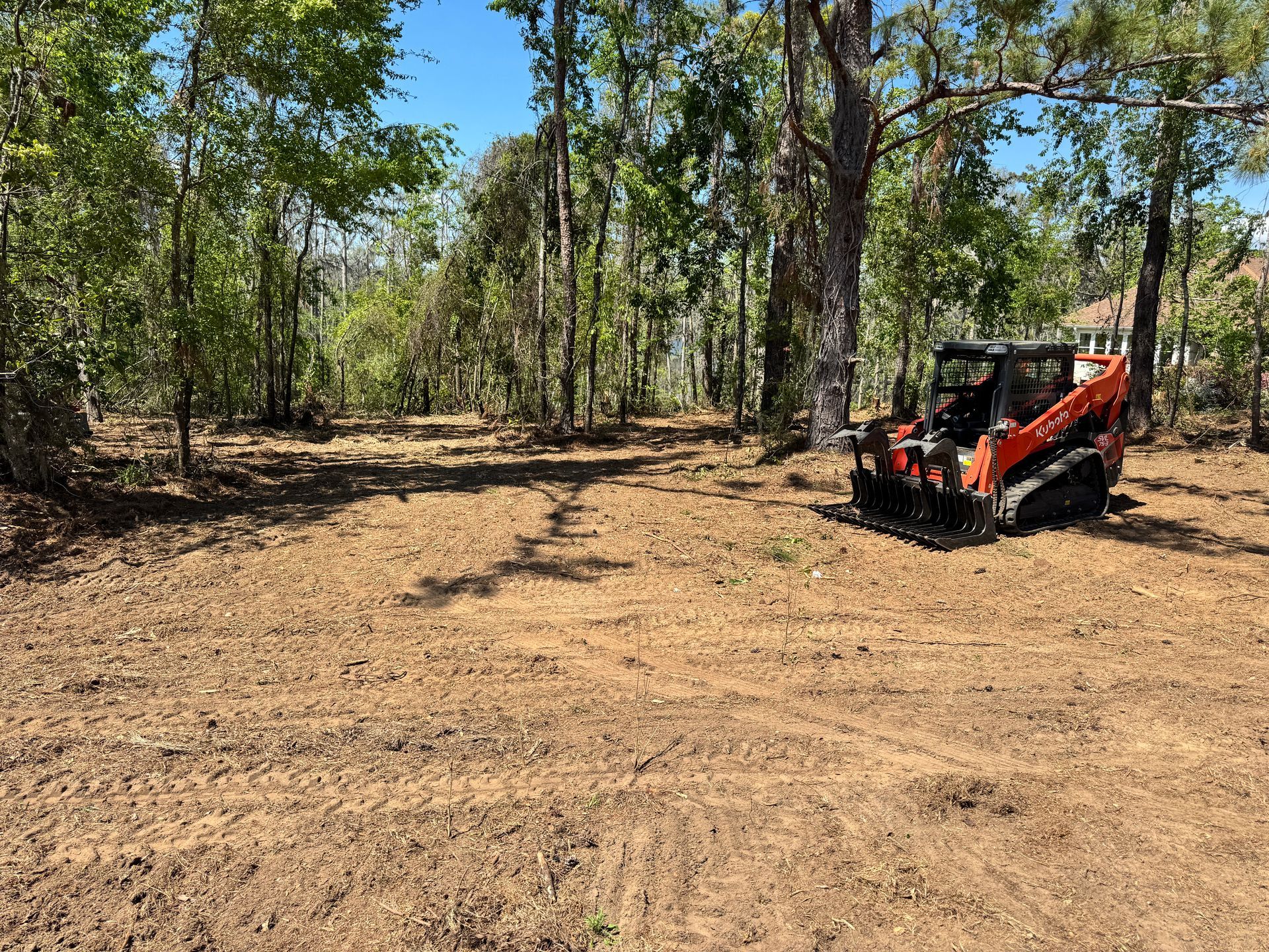 A bulldozer is parked in a dirt field surrounded by trees.