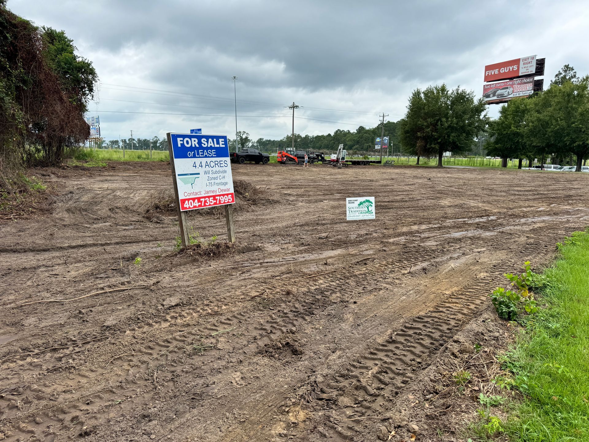 A for sale sign is in the middle of a dirt field.