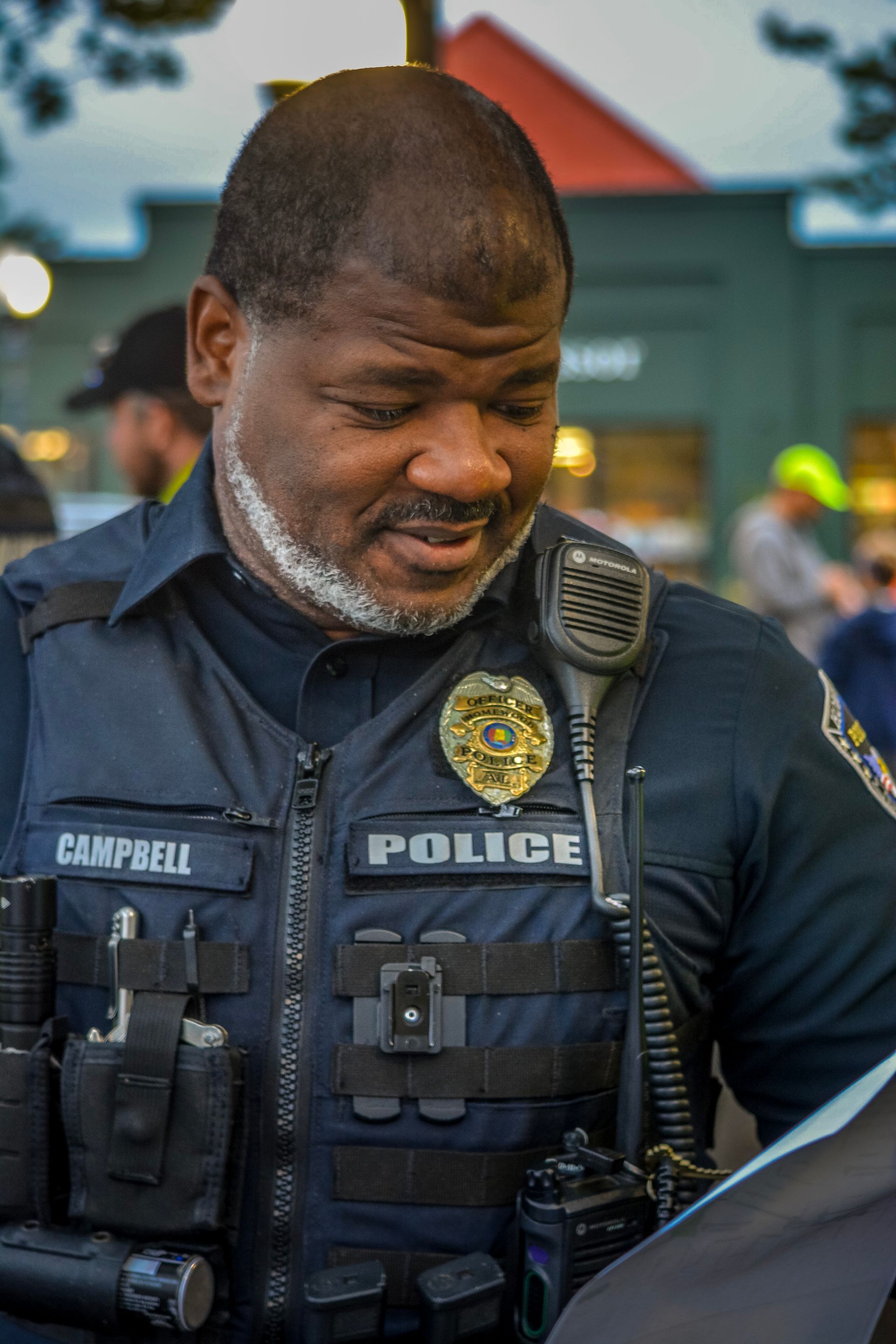 A police officer is talking on a walkie talkie while looking at a piece of paper.