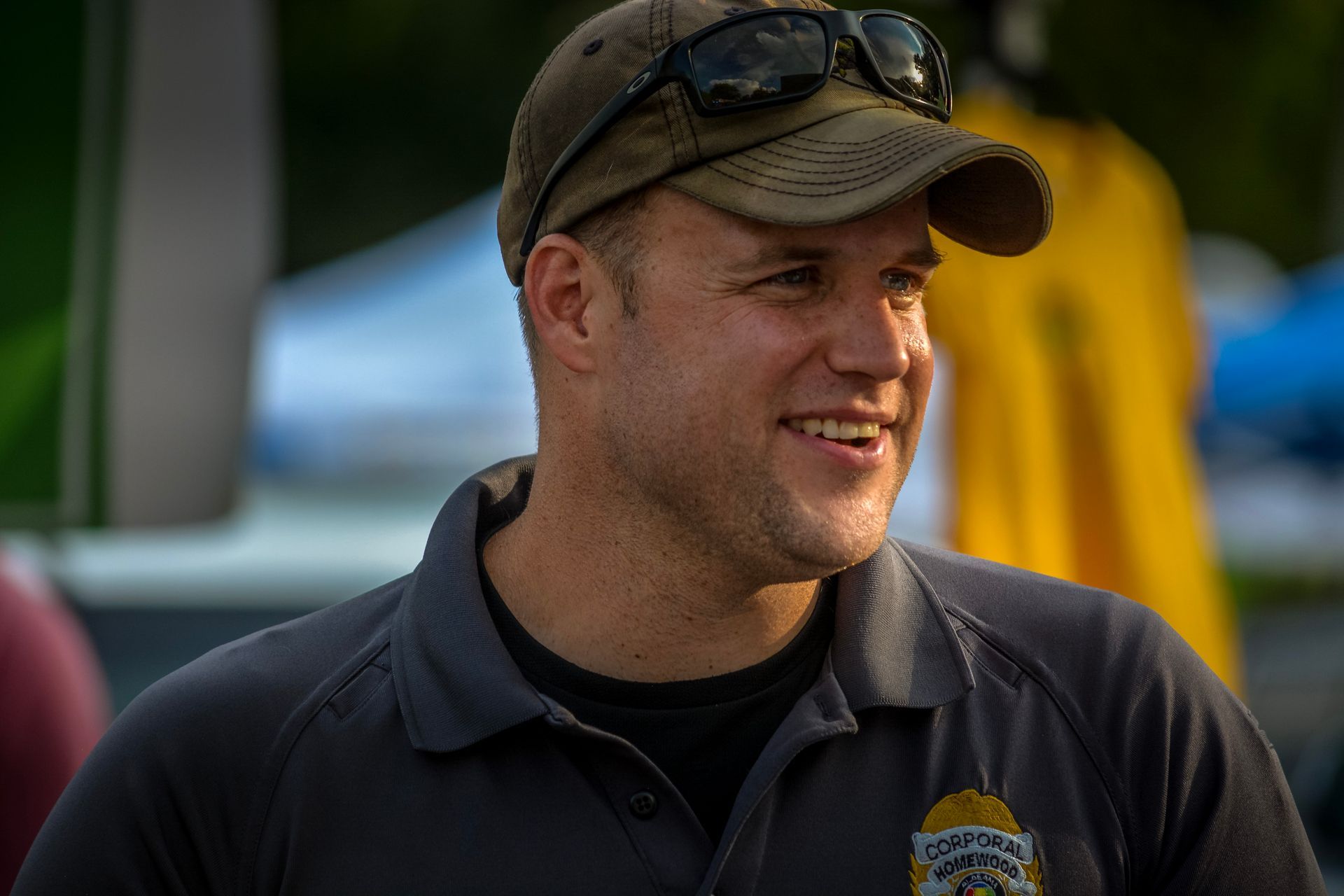 A man wearing a hat and sunglasses is smiling.