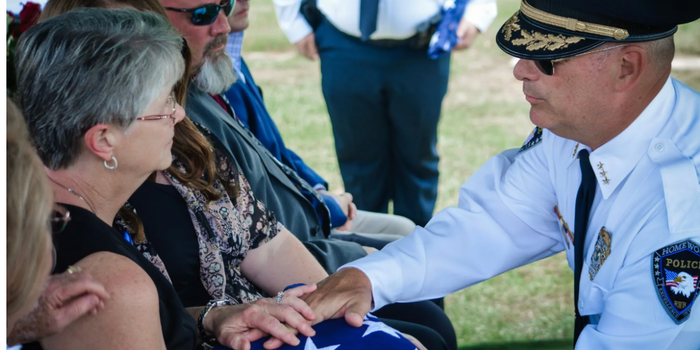 A man in a police uniform is putting a flag on a woman 's lap.