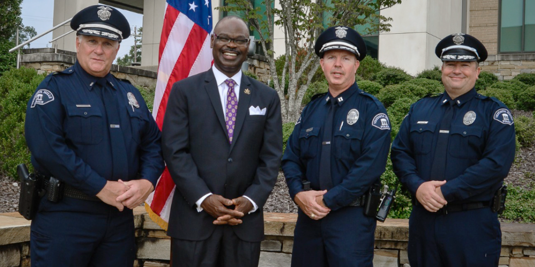 A group of police officers are posing for a picture in front of an american flag.