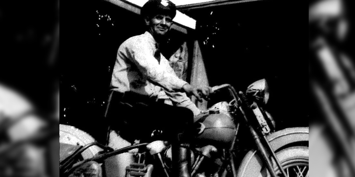 A man is sitting on a motorcycle in a black and white photo.