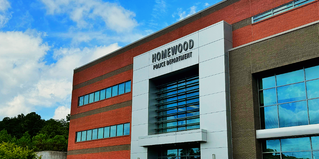 A large brick building with a lot of windows and trees in the background.