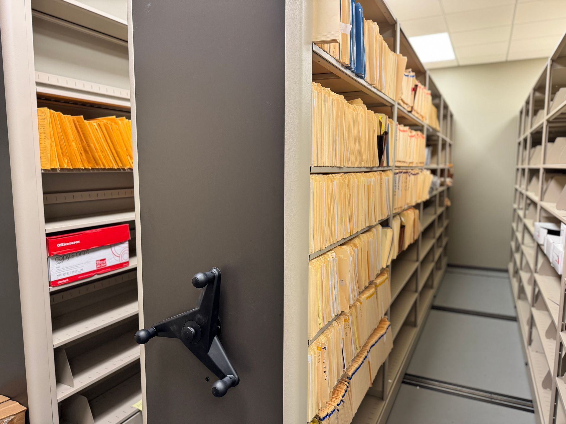 A row of shelves filled with lots of files and boxes.