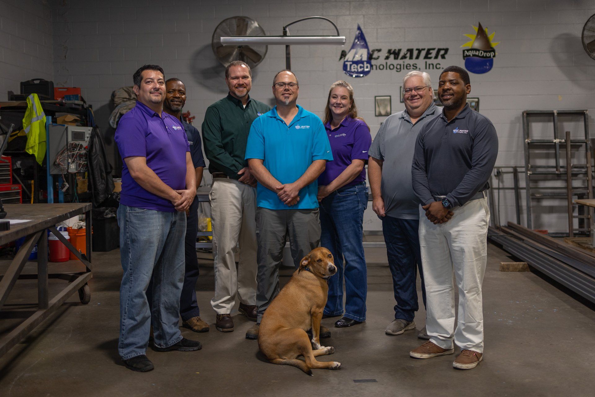 A group of people and a dog are posing for a picture in a garage.