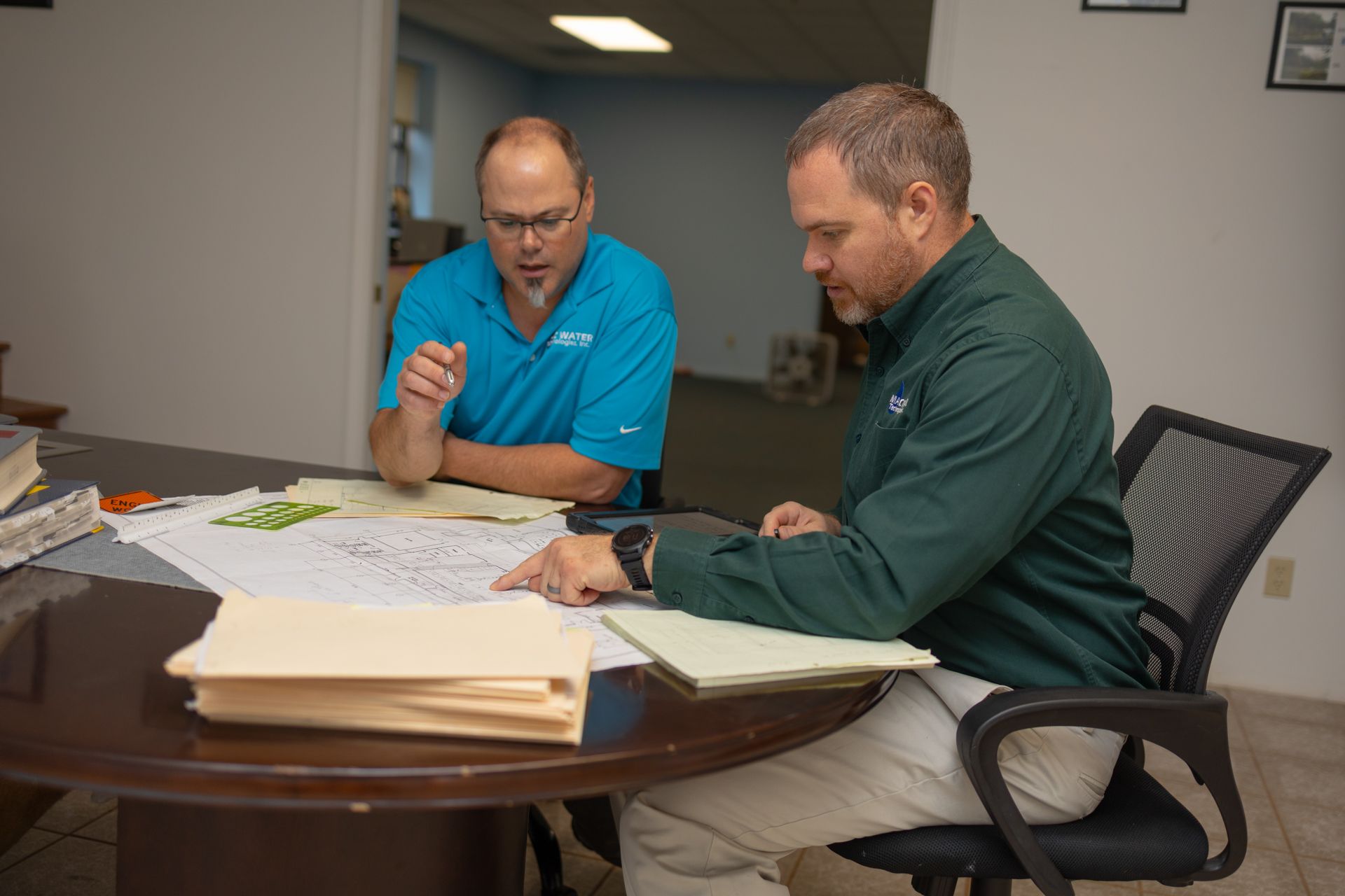two MAC Water employees looking at blueprints at a table in an office