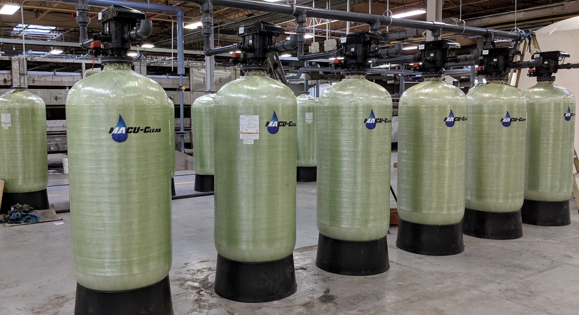 A row of water tanks are lined up in a warehouse.