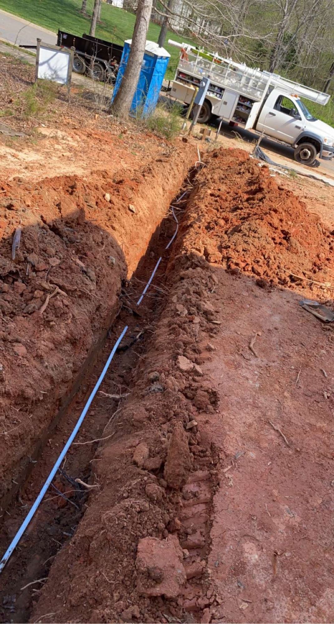 A white truck is parked next to a large hole in the ground.