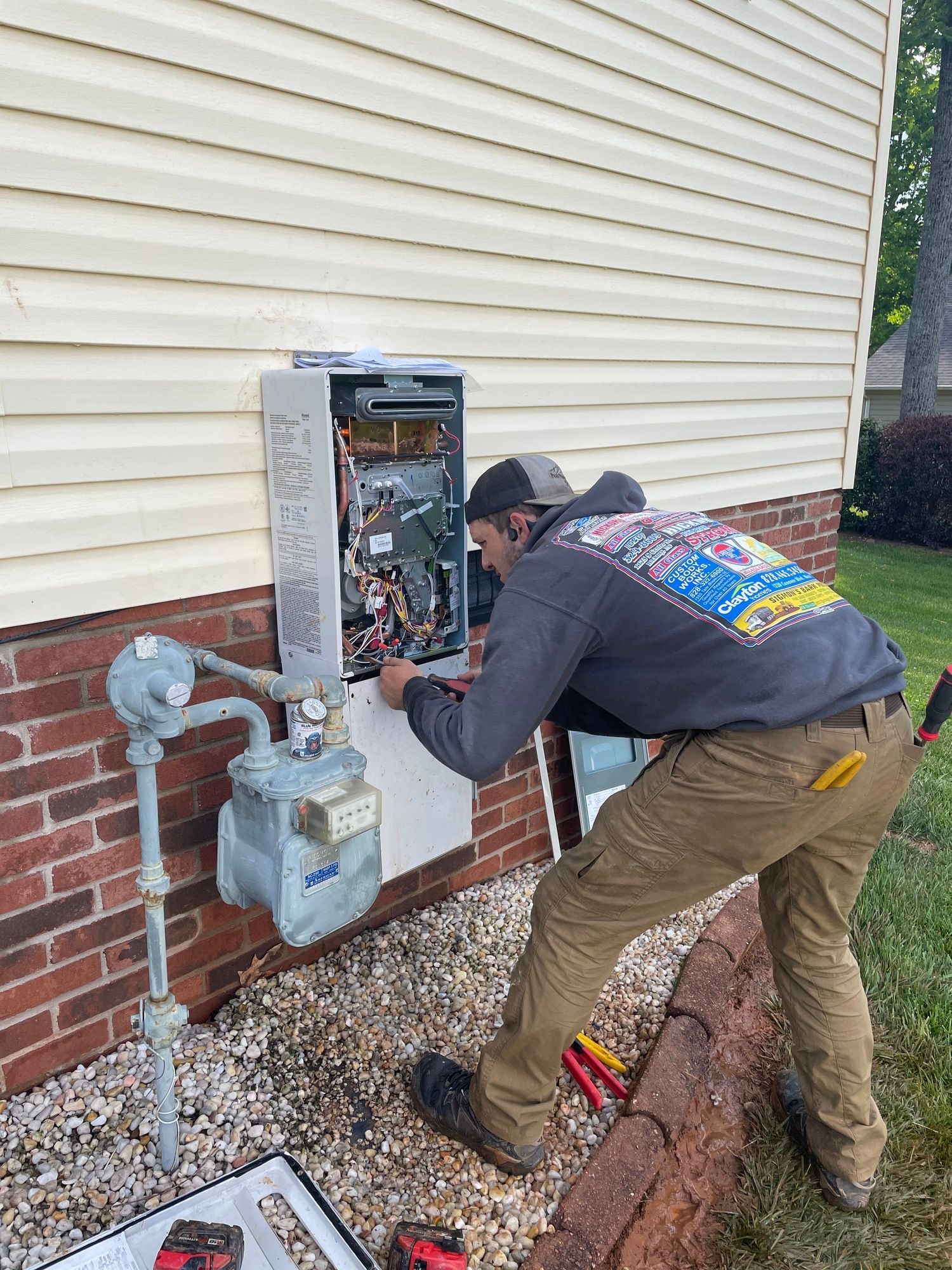 A man is working on a gas meter on the side of a house.
