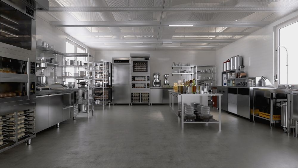 A wide shot of a modern, clean, professional stainless steel commercial kitchen with appliances and workstations.