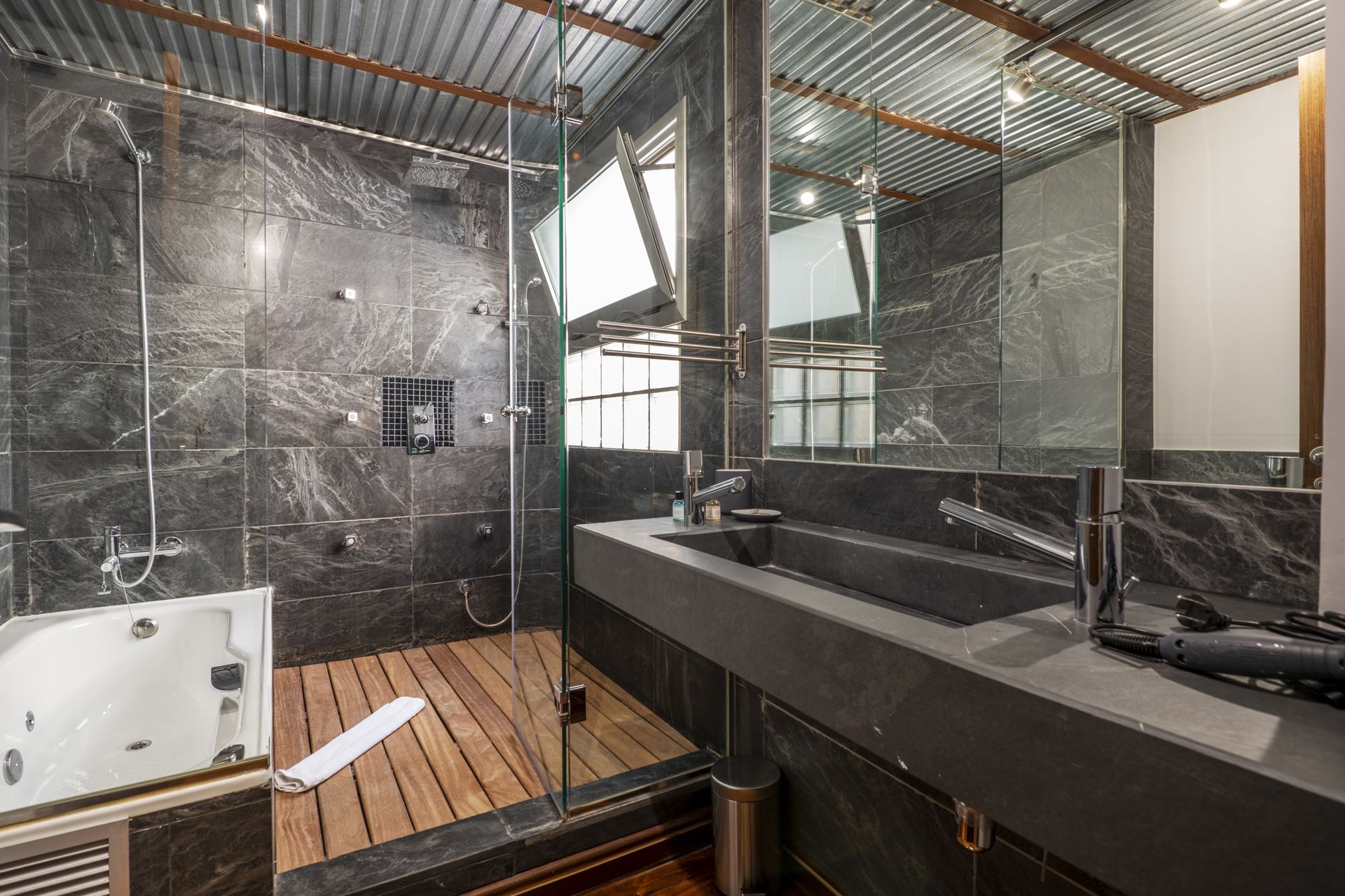 A bathroom with a sink , tub , shower and mirror.