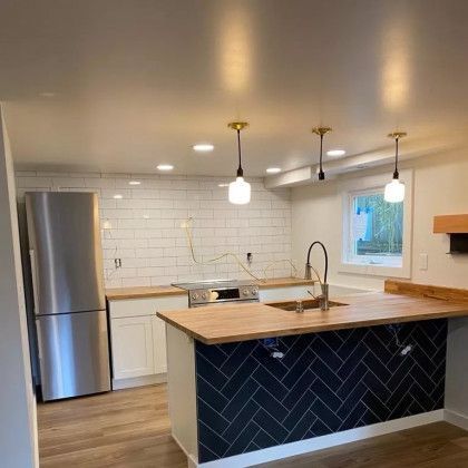 A kitchen with stainless steel appliances , a large island , a sink , and a refrigerator.