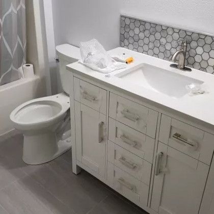 A bathroom with a toilet , sink , and cabinets.